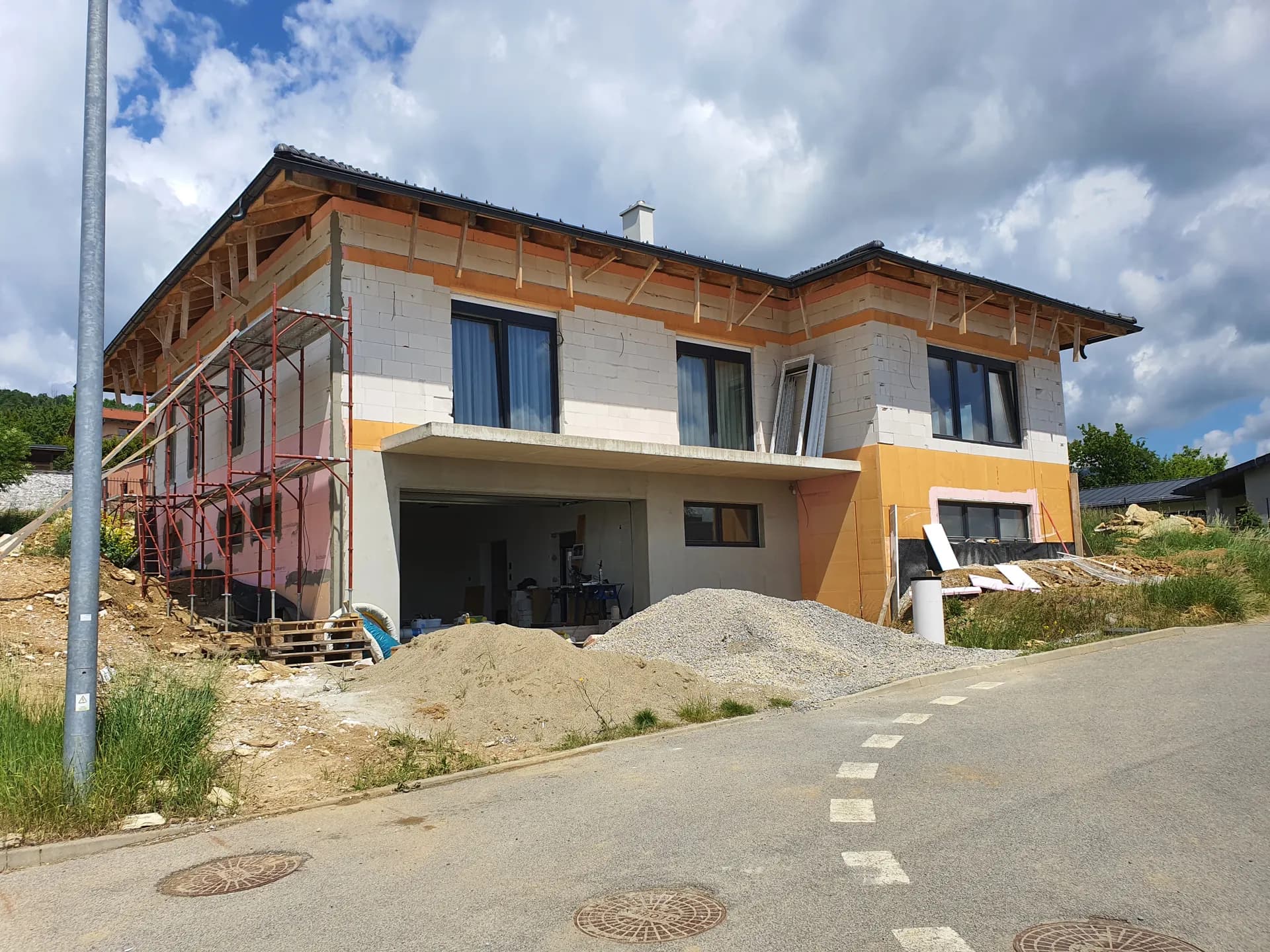 Jún 2022 — lešenie na uličnej strane a prvé dosky zatepľovacieho systému