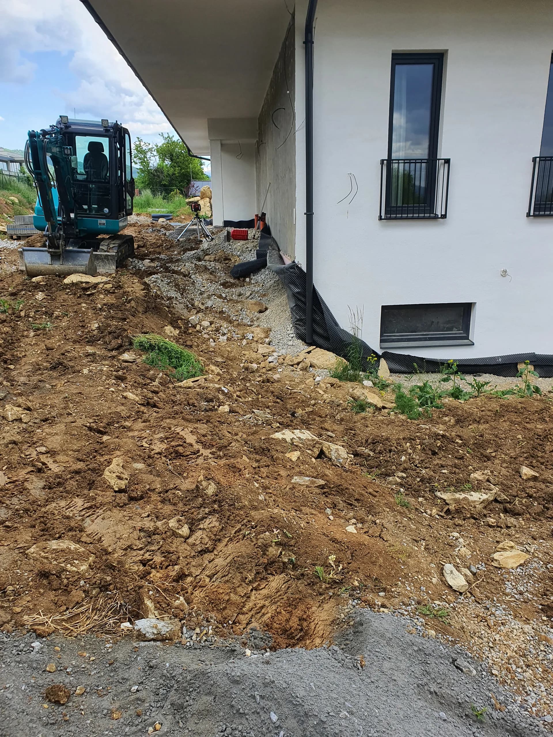Máj 2023 — výkop ryhy pre drenáž a štrkový zásyp po obvode domu