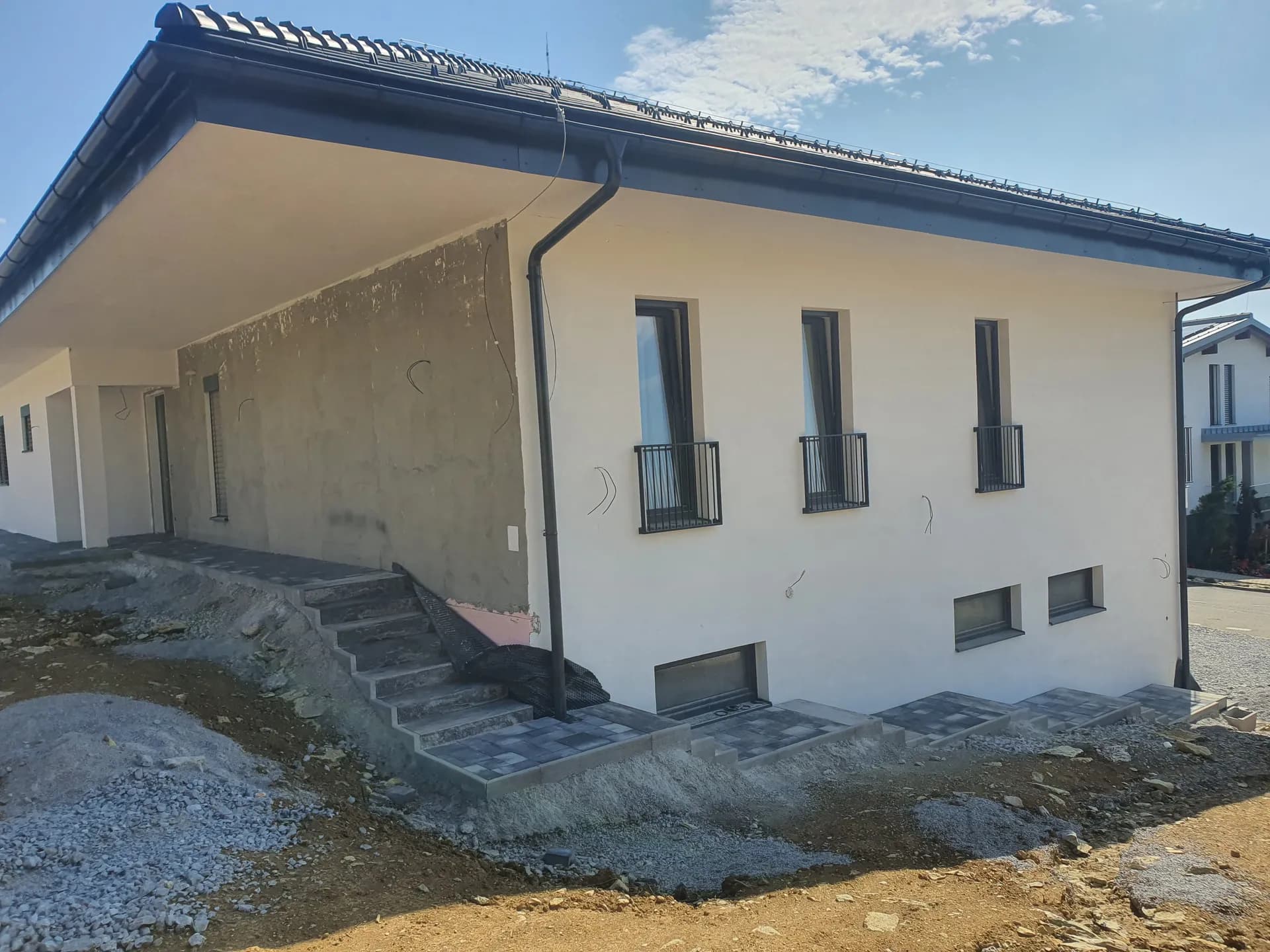 Júl 2023 — hotová fasáda, francúzske balkóny a spevnené plochy pri vstupe