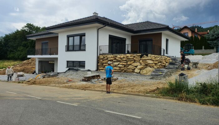 Novostavba luxusného rodinneho domu s moderným vzhľadom, stierkovaná fasáda, drevený obklad, plot z prírodného kameňa. Stavba domu na kľúč