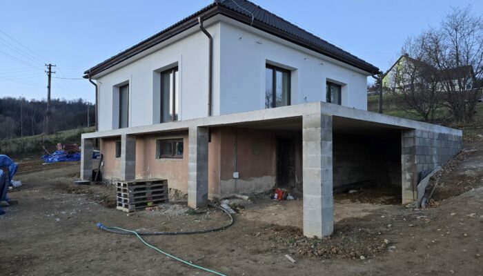 Pohľad na práve zrekonštruovaný rodinný dom z pristavenou monolitickou terasou a čerstvo dokončenou bielou fasádou