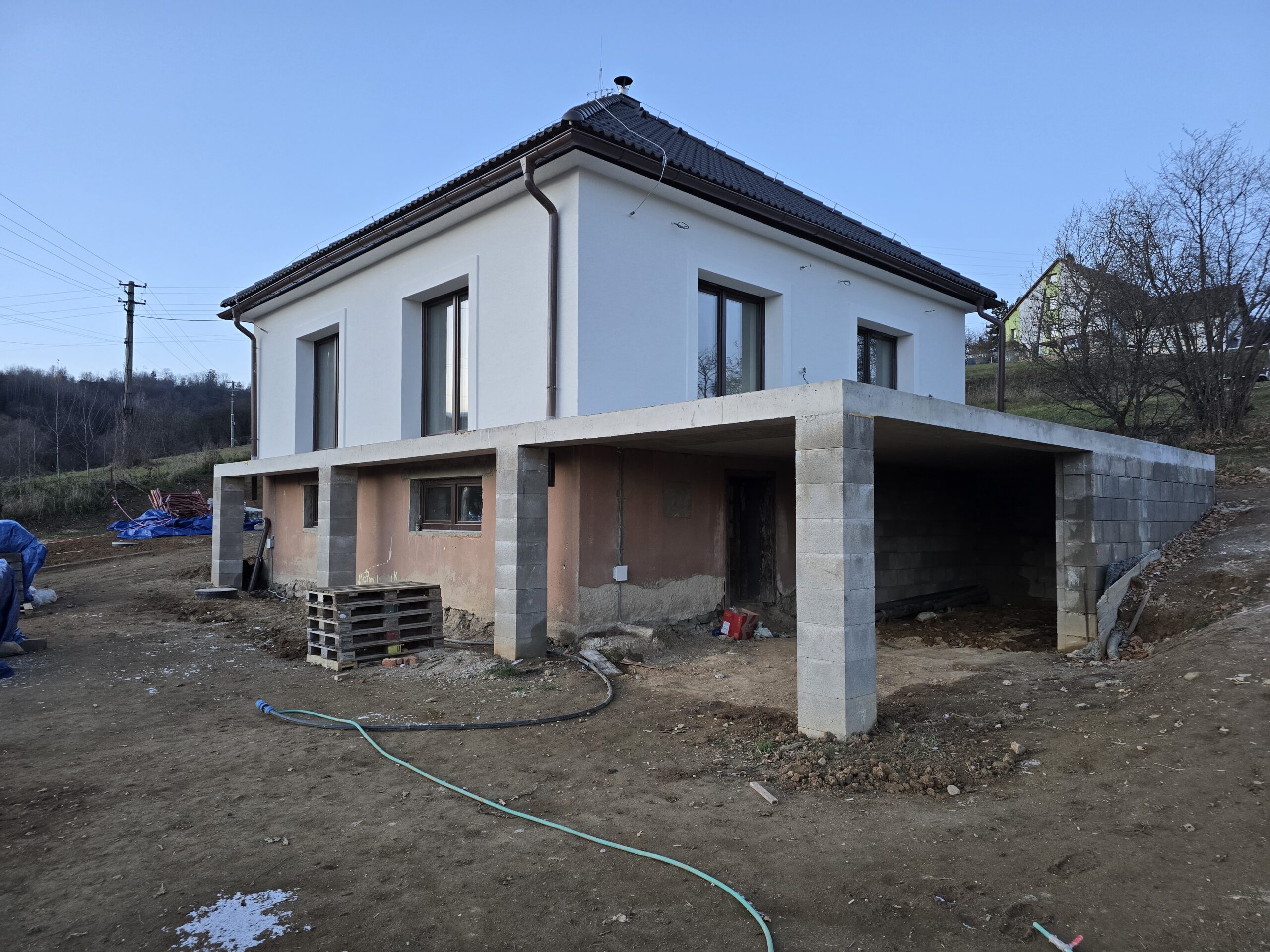 Pohľad na práve zrekonštruovaný rodinný dom z pristavenou monolitickou terasou a čerstvo dokončenou bielou fasádou
